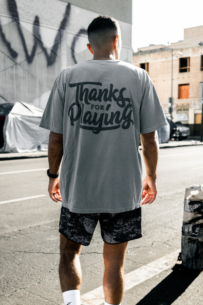 The back side of the grey logo tee worn in the street.