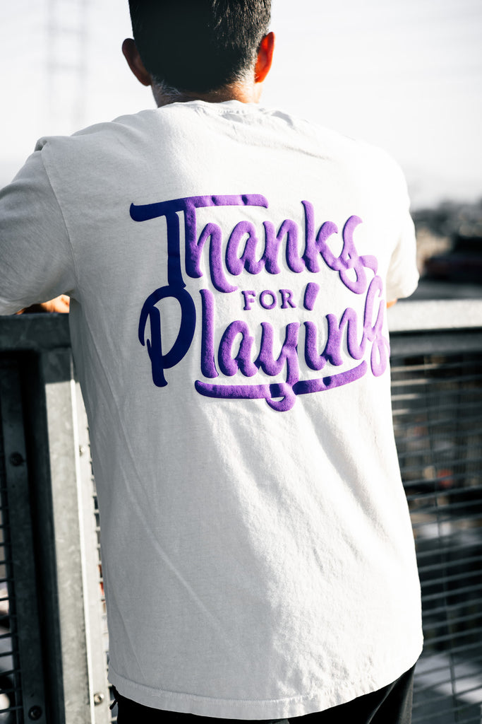 The back side of the purple logo tee worn on the street.